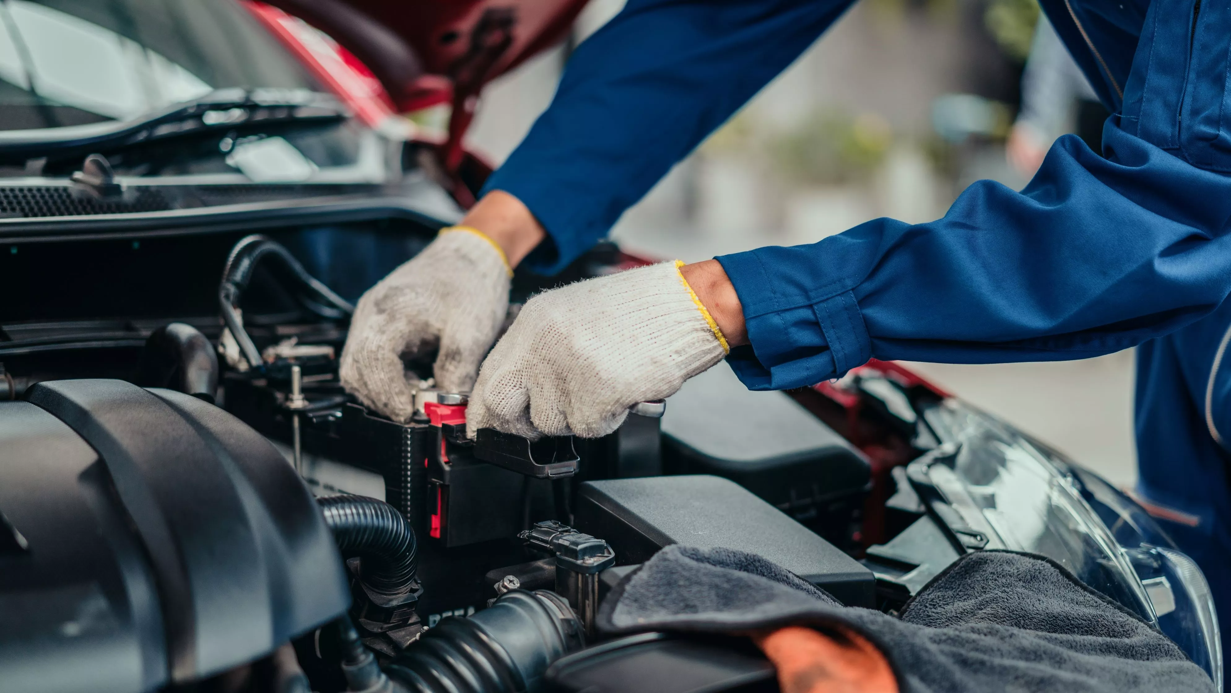 Kfz-Mechatroniker arbeitet an geöffneter Motorhaube